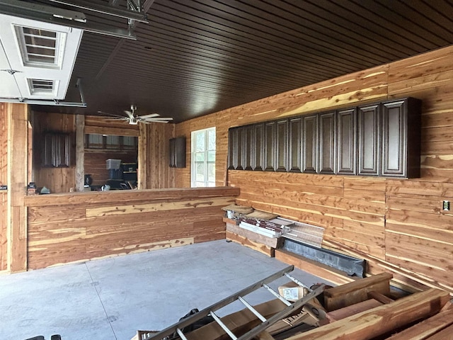  - living room featuring wooden walls, a ceiling fan, and concrete flooring