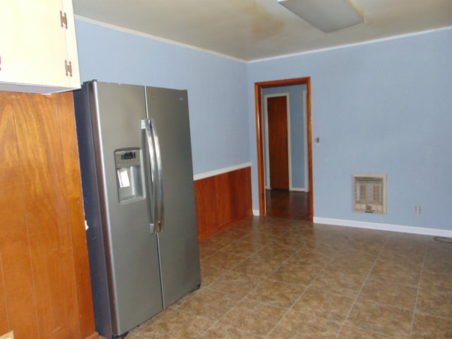 kitchen with stainless steel fridge, heating unit, and wood walls