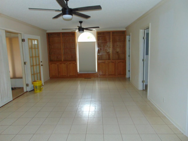 tiled spare room featuring built in shelves and crown molding