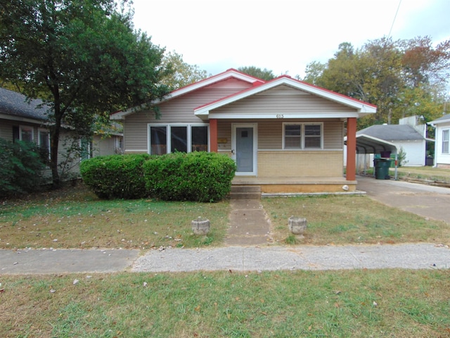 bungalow-style house with a carport, covered porch, and a front lawn