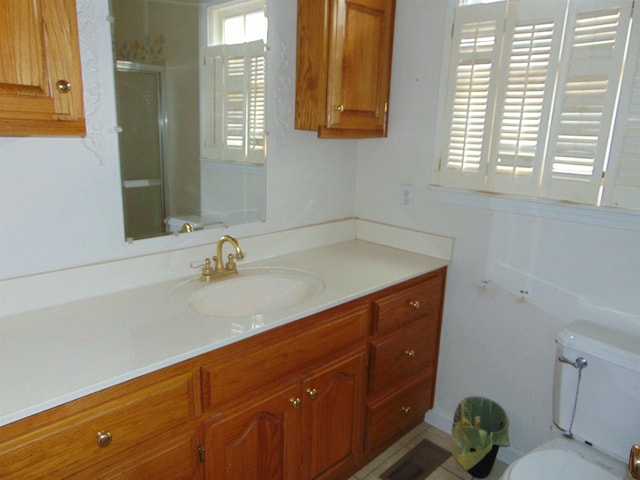 bathroom featuring vanity, toilet, and a shower with shower door