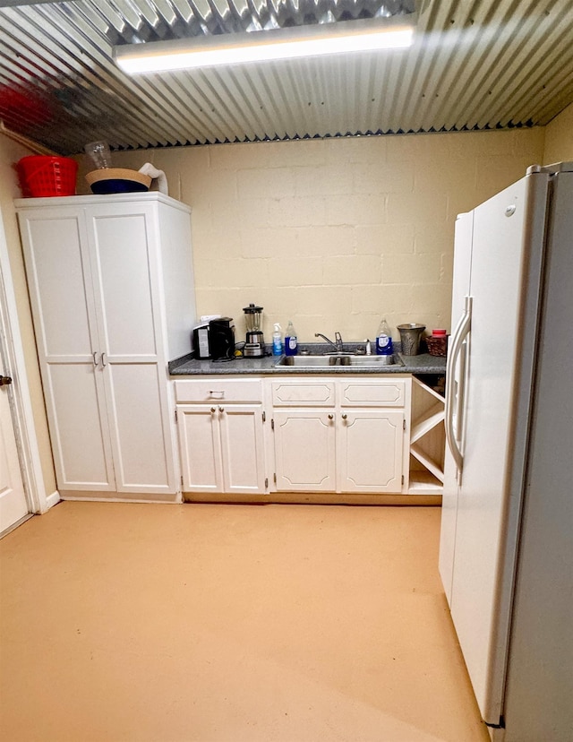 kitchen featuring white fridge with ice dispenser, white cabinets, and sink