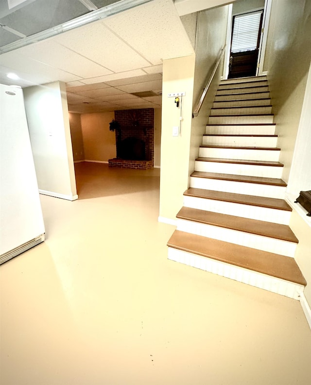 stairs featuring a paneled ceiling, a fireplace, and concrete floors