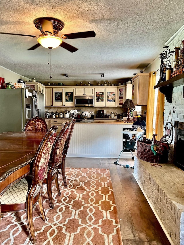 dining space with ceiling fan, a fireplace, wood-type flooring, and a textured ceiling