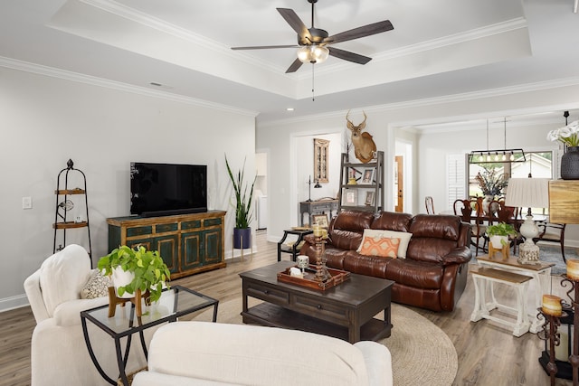  - living area featuring a raised ceiling, wood finished floors, ceiling fan, and ornamental molding