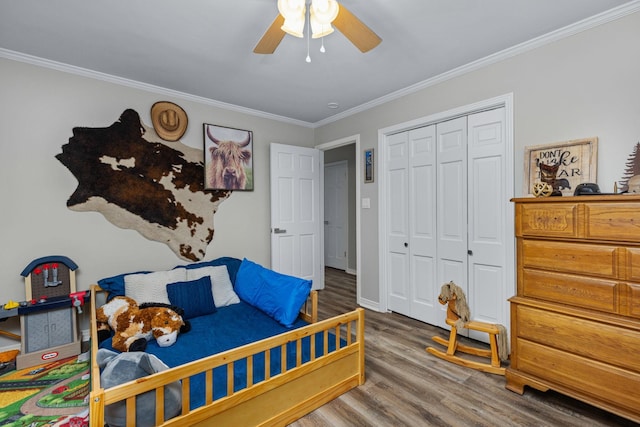 bedroom with hardwood / wood-style flooring, ornamental molding, ceiling fan, and a closet