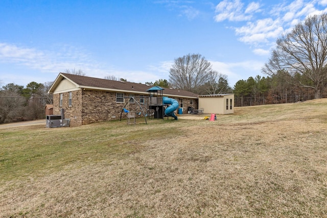 rear view of property with a shed, a lawn, and a playground