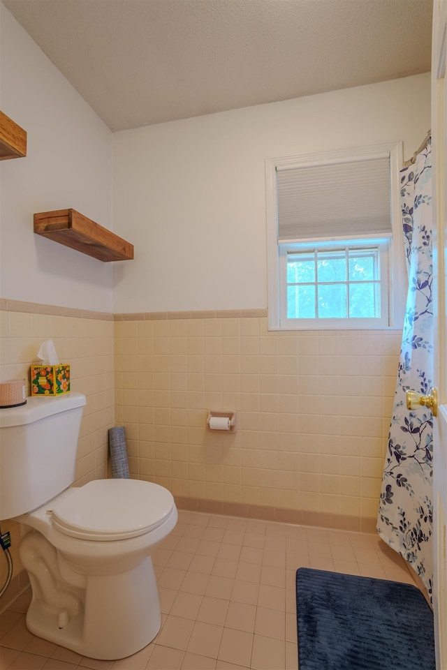  - full bathroom featuring toilet, tile walls, wainscoting, tile patterned floors, and curtained shower