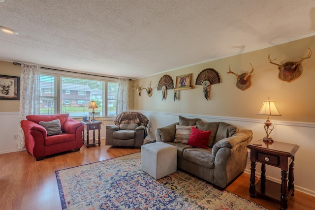  - living room featuring a textured ceiling, wood finished floors, and a wainscoted wall