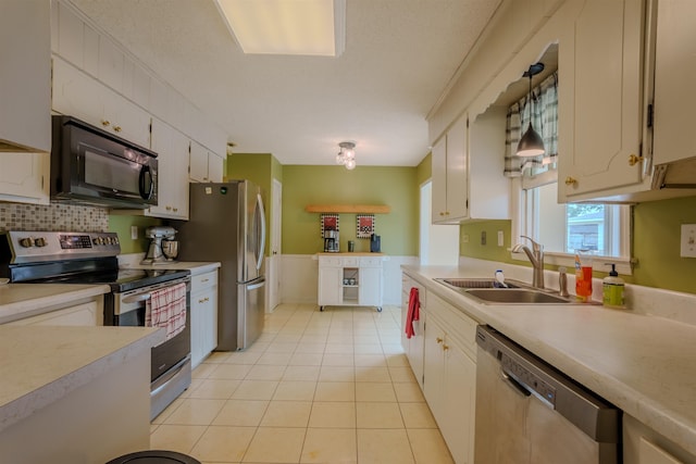  - kitchen featuring appliances with stainless steel finishes, light countertops, light tile patterned floors, and white cabinetry