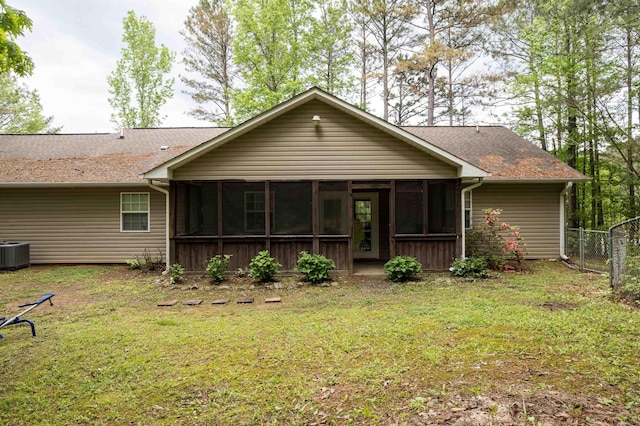  - rear view of property with fence, a shingled roof, a sunroom, cooling unit, and a lawn