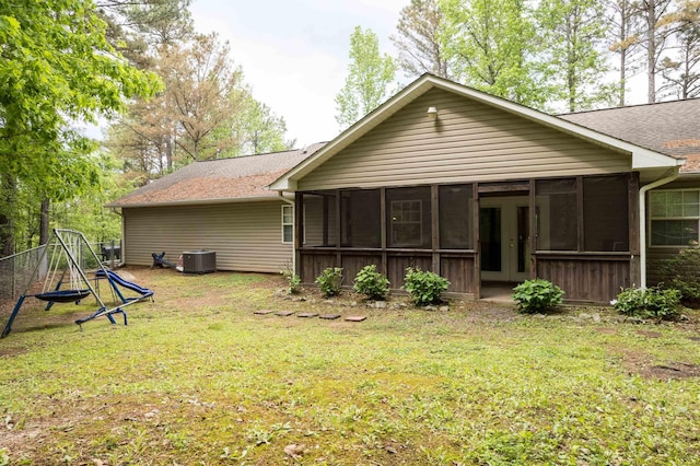  - rear view of property with a sunroom, a lawn, central AC, and roof with shingles