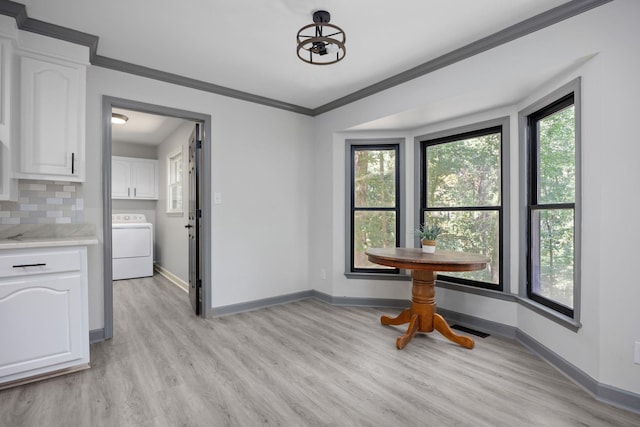 dining area featuring light wood-style flooring, baseboards, ornamental molding, and washer / dryer