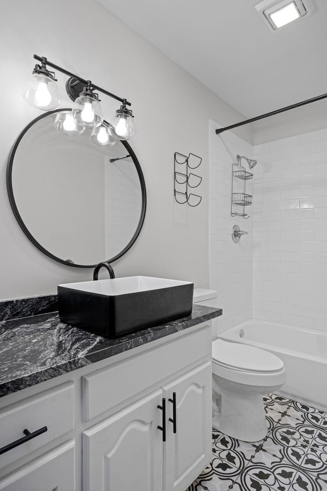 bathroom featuring vanity, tile patterned flooring, washtub / shower combination, and toilet