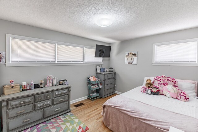  - bedroom with light wood-type flooring, baseboards, visible vents, and a textured ceiling