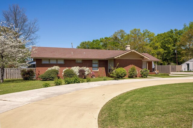 - single story home with brick siding, fence, and a front lawn