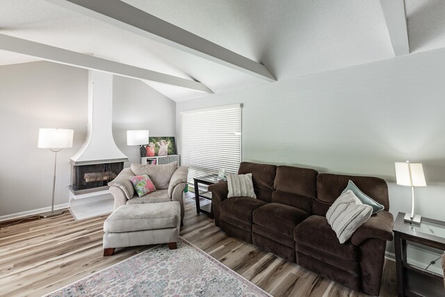  - living area with a multi sided fireplace, baseboards, vaulted ceiling with beams, and wood finished floors