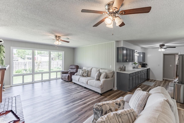 - living area featuring ceiling fan, wood finished floors, and a textured ceiling