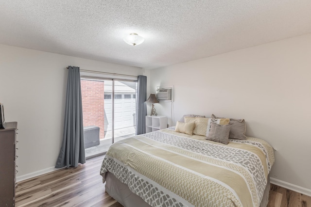  - bedroom featuring a textured ceiling, access to exterior, baseboards, and wood finished floors