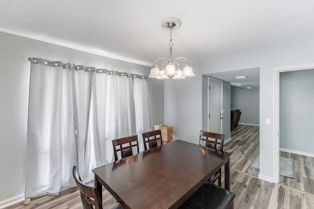  - dining room featuring light wood-style flooring, a chandelier, and baseboards