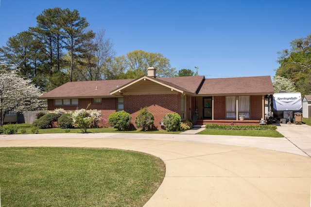  - ranch-style home with roof with shingles, curved driveway, a front lawn, a porch, and brick siding