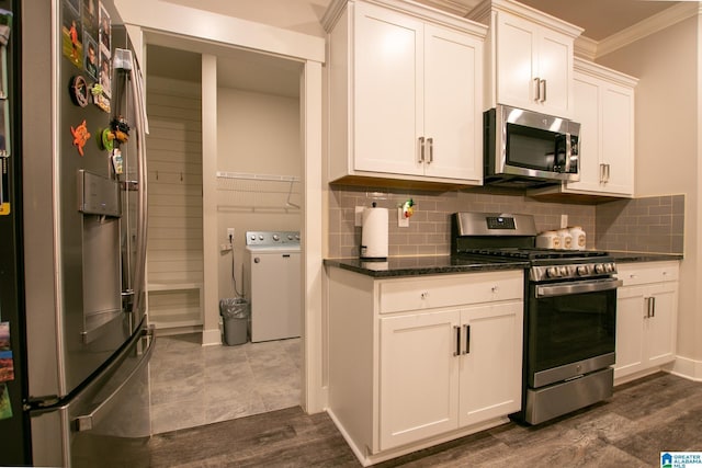  - kitchen featuring appliances with stainless steel finishes, ornamental molding, backsplash, white cabinetry, and washing machine and dryer
