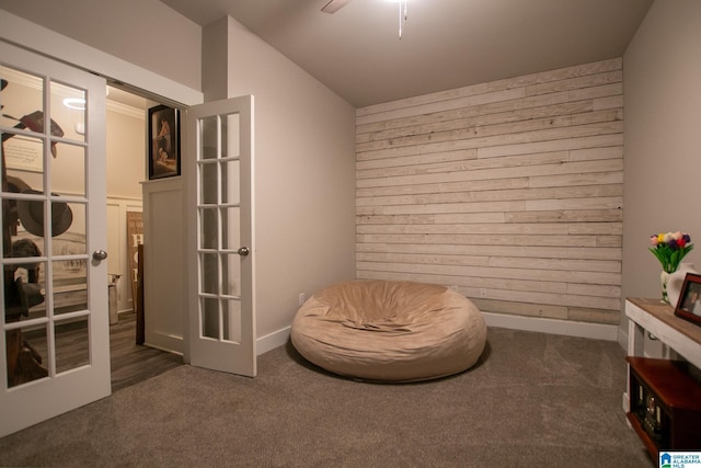  - living area featuring wood walls, carpet flooring, ceiling fan, and french doors