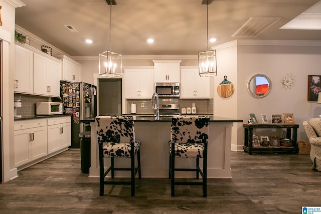  - kitchen with stainless steel appliances, dark countertops, crown molding, tasteful backsplash, and a kitchen bar