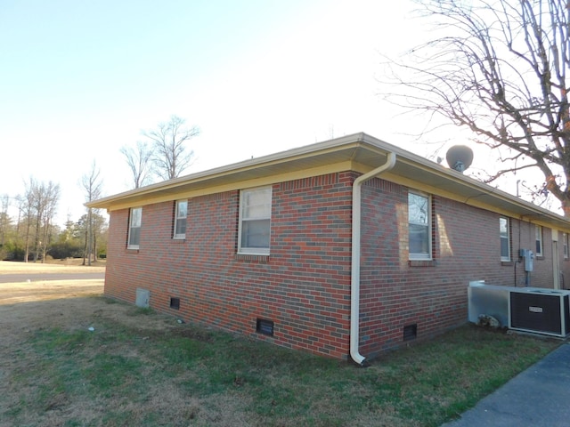 view of property exterior with crawl space, brick siding, a yard, and central AC