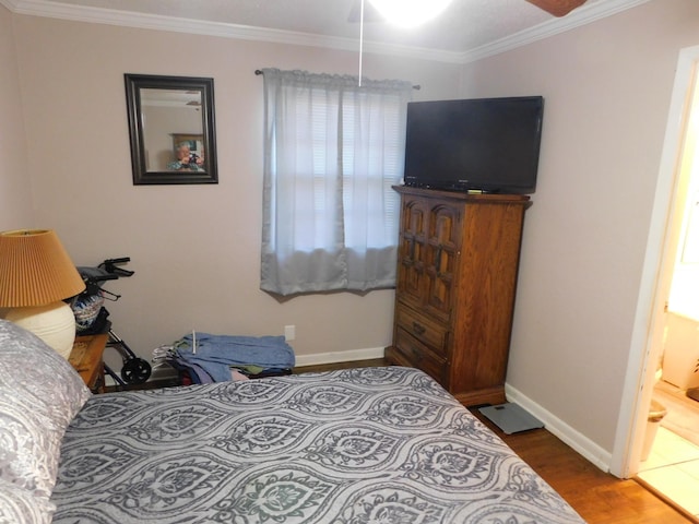 bedroom featuring baseboards, ensuite bathroom, wood finished floors, and crown molding