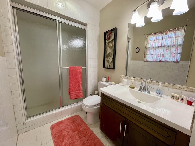  - bathroom with vanity, a shower stall, toilet, tile patterned flooring, and tile walls