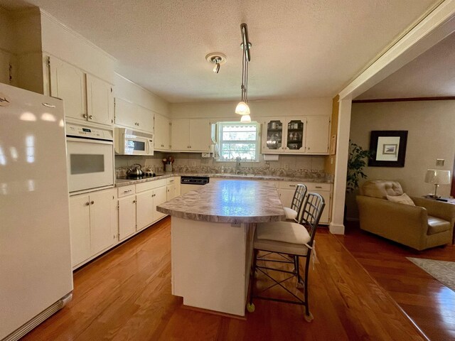  - kitchen with white appliances, a sink, white cabinets, crown molding, and wood finished floors