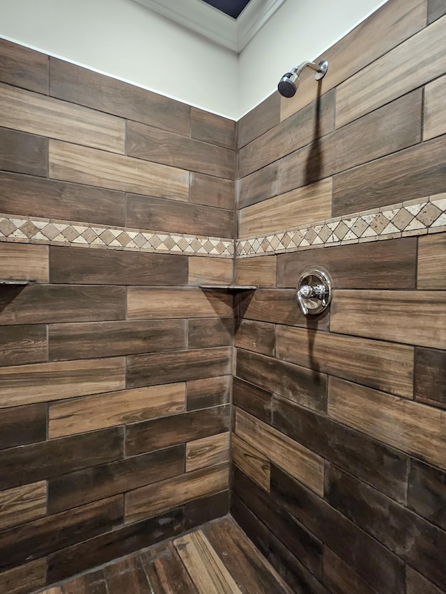 bathroom with a tile shower and crown molding