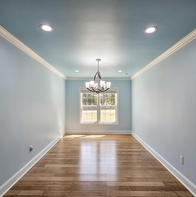 unfurnished dining area with wood-type flooring, ornamental molding, and a chandelier