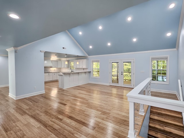 unfurnished living room featuring sink, french doors, crown molding, and light hardwood / wood-style flooring