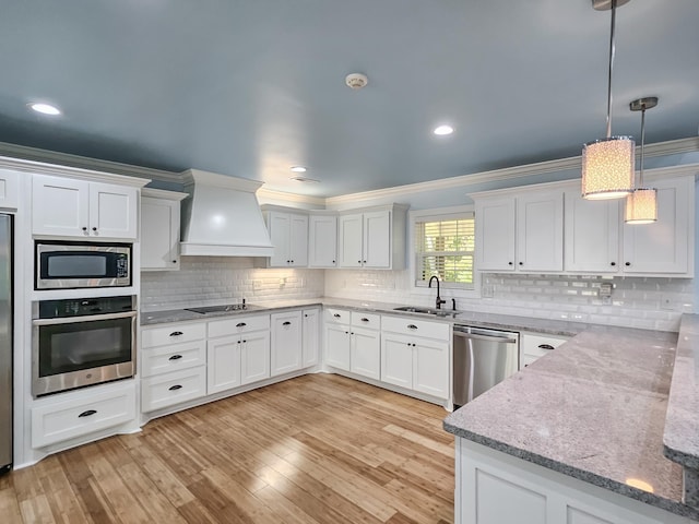 kitchen with premium range hood, sink, white cabinets, and stainless steel appliances