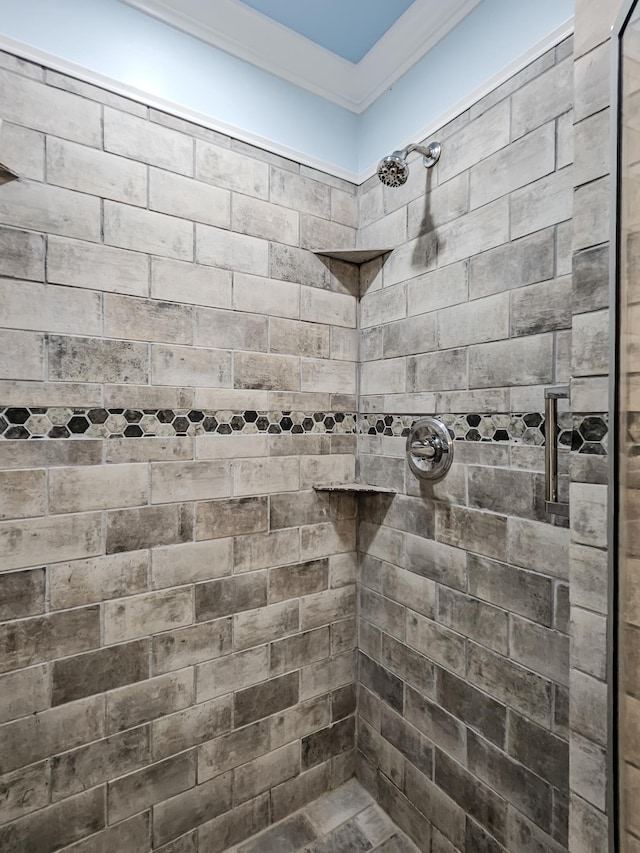 bathroom with a tile shower and crown molding