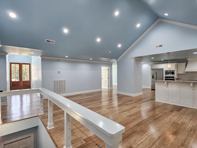 unfurnished living room featuring french doors, high vaulted ceiling, and light wood-type flooring