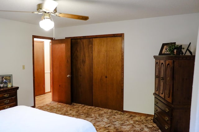 bedroom with ceiling fan, light carpet, and a closet