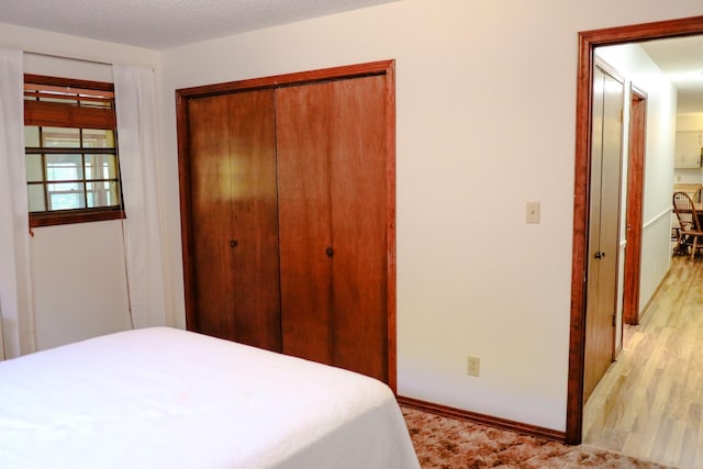 bedroom featuring a closet, a textured ceiling, and light wood-type flooring