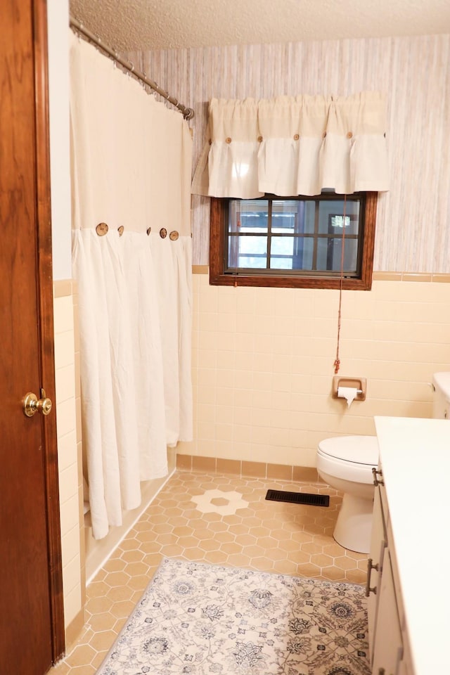 bathroom featuring a shower with curtain, vanity, tile walls, tile patterned flooring, and toilet