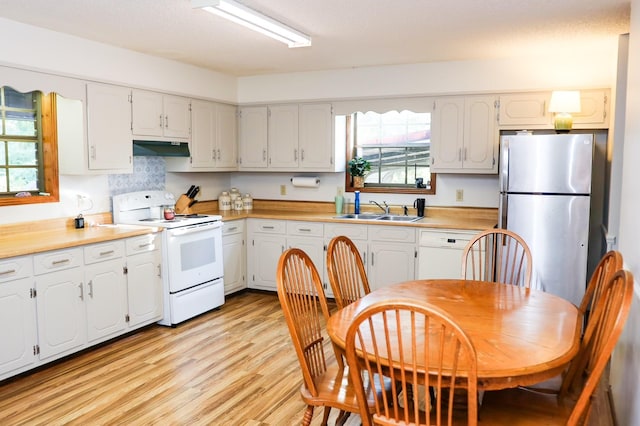 kitchen with white range with electric cooktop, stainless steel fridge, white cabinetry, and sink