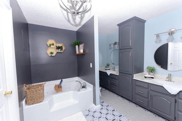 bathroom featuring tile patterned flooring, vanity, a bathing tub, and a textured ceiling