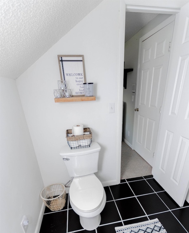 bathroom with toilet, a textured ceiling, and tile patterned floors