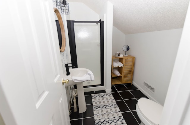 bathroom featuring tile patterned floors, toilet, a shower with door, and a textured ceiling