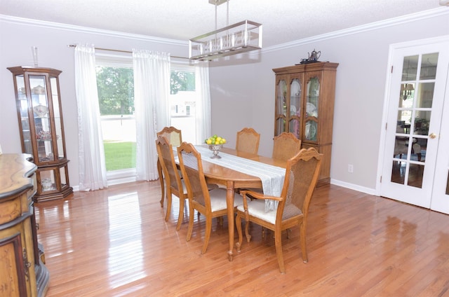 dining space featuring a textured ceiling, light hardwood / wood-style floors, and crown molding