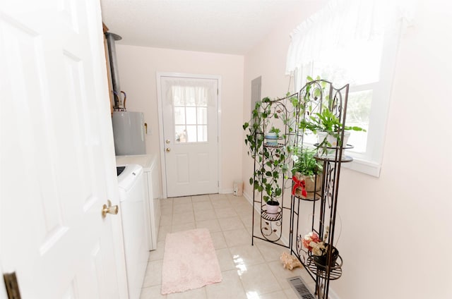 entryway featuring plenty of natural light, light tile patterned floors, gas water heater, and independent washer and dryer