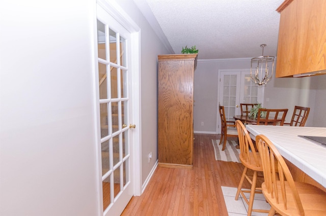 dining room featuring french doors, a textured ceiling, light hardwood / wood-style flooring, and crown molding