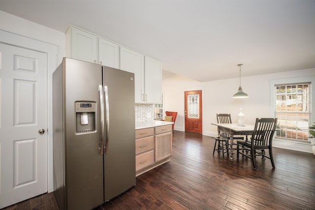 kitchen with dark wood-type flooring, hanging light fixtures, stainless steel fridge with ice dispenser, tasteful backsplash, and white cabinetry