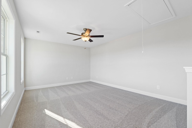 unfurnished room with carpet floors, attic access, visible vents, and a wealth of natural light